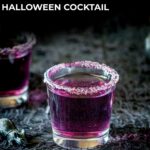 pin image: a purple cocktail in a shot glass, on a halloween inspired table with text overlaid
