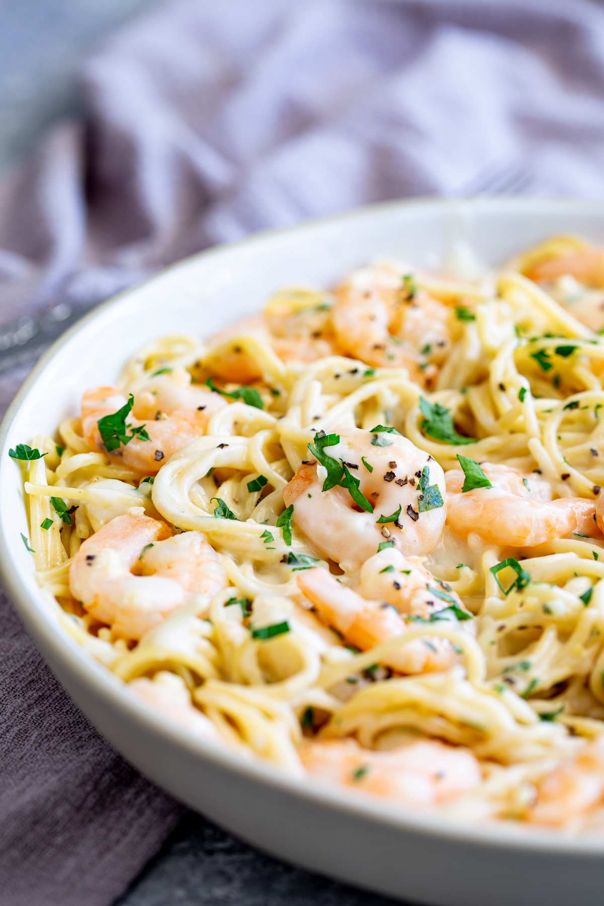 a large dish of spaghetti with a cream sauce and shrimp mixed through it