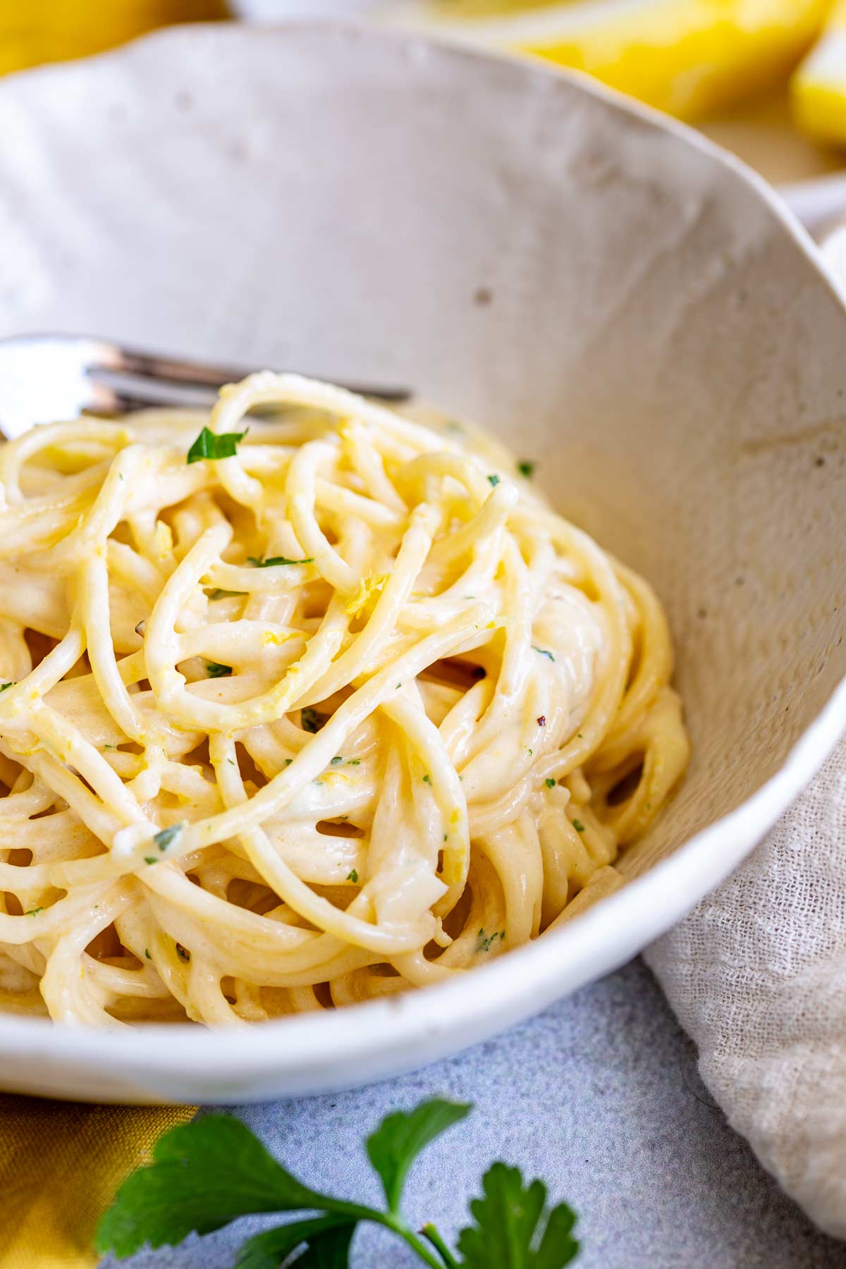 a rustic white bowl with a portion of creamy lemon pasta in it