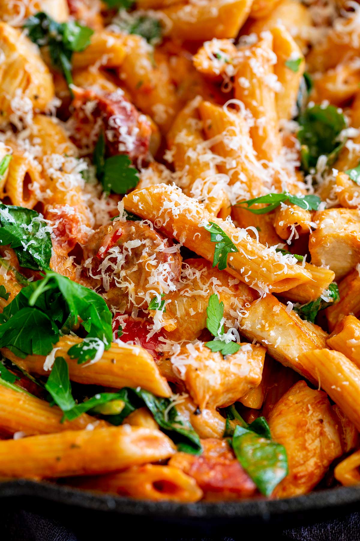 penne pasta in a creamy tomato sauce with parmesan and herbs on top