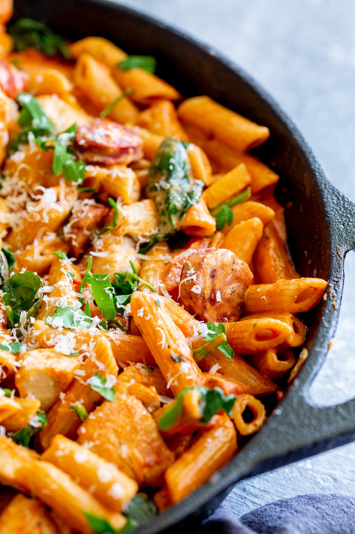 close up on a piece of chorizo in a pan of pasta