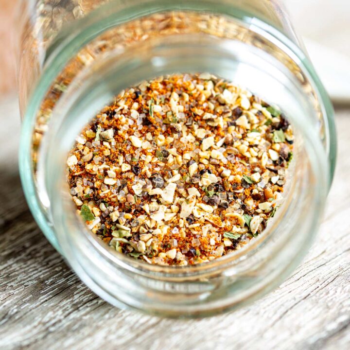 Close up on garlic pepper seasoning in a glass jar that is lying down