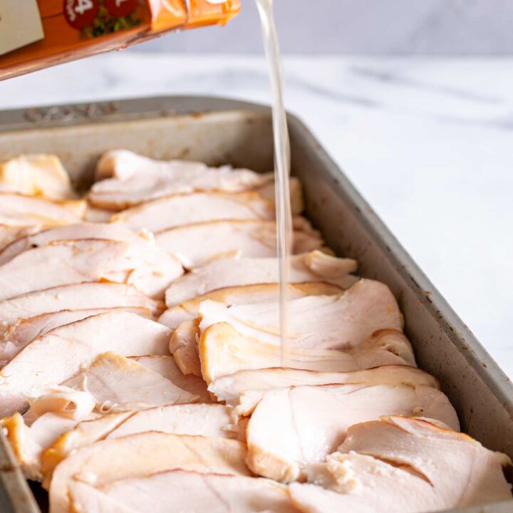 close up on the flow of broth from a carton onto slices of turkey