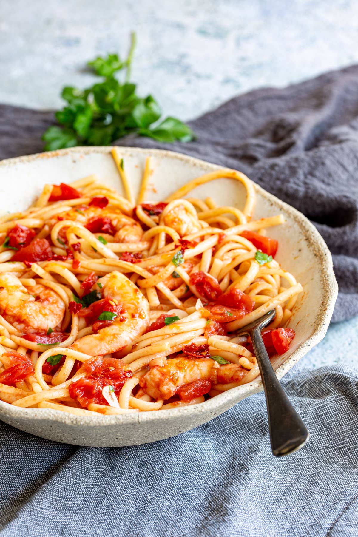 a fork sitting in a bowl of spaghetti with shrimp and tomato sauce