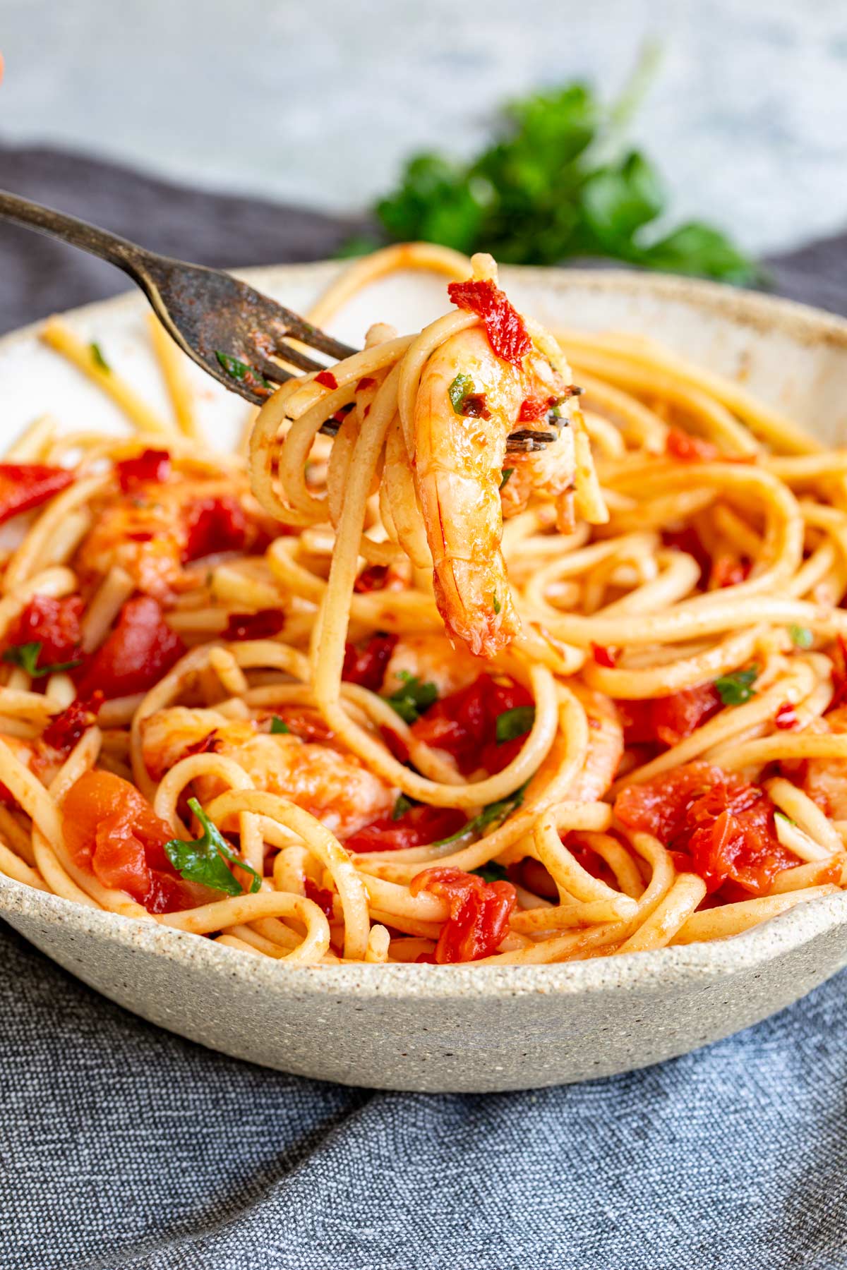 a fork lifting a shrimp and some spaghetti from a bowl