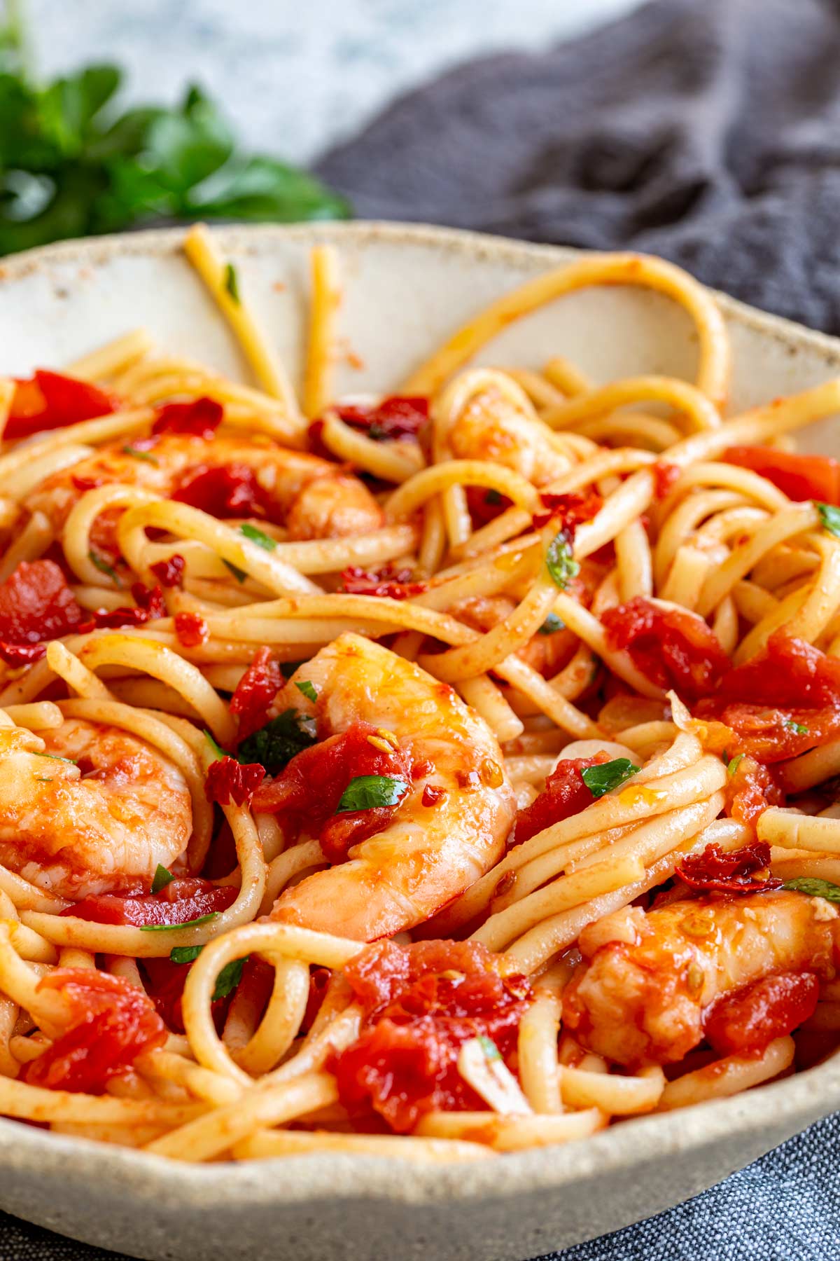 shrimp with a spicy tomato sauce mixed with spaghetti in a rustic bowl
