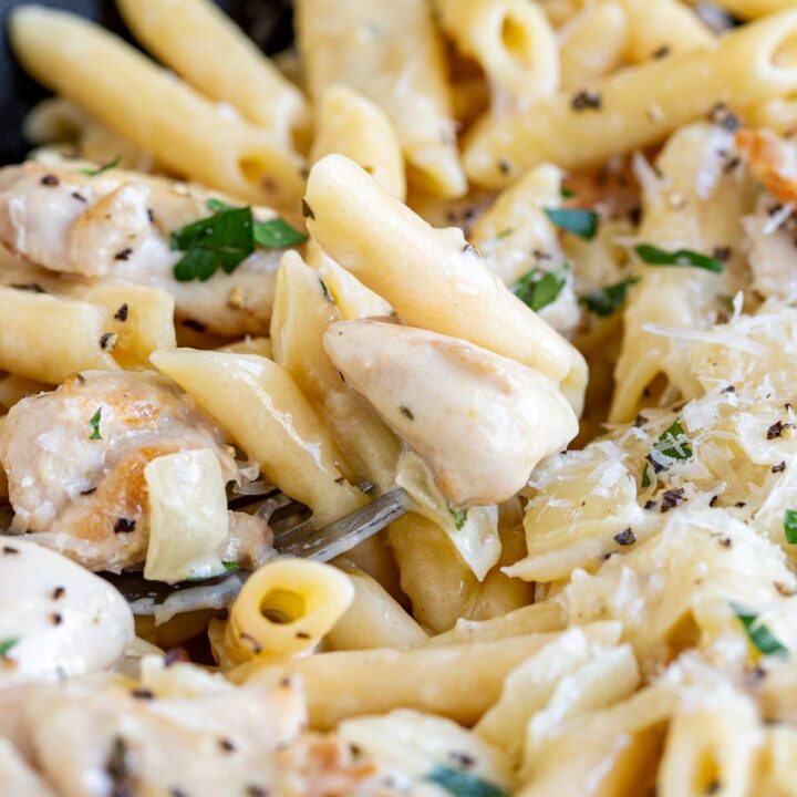 close up on a fork in a bowl of cheesy chicken pasta