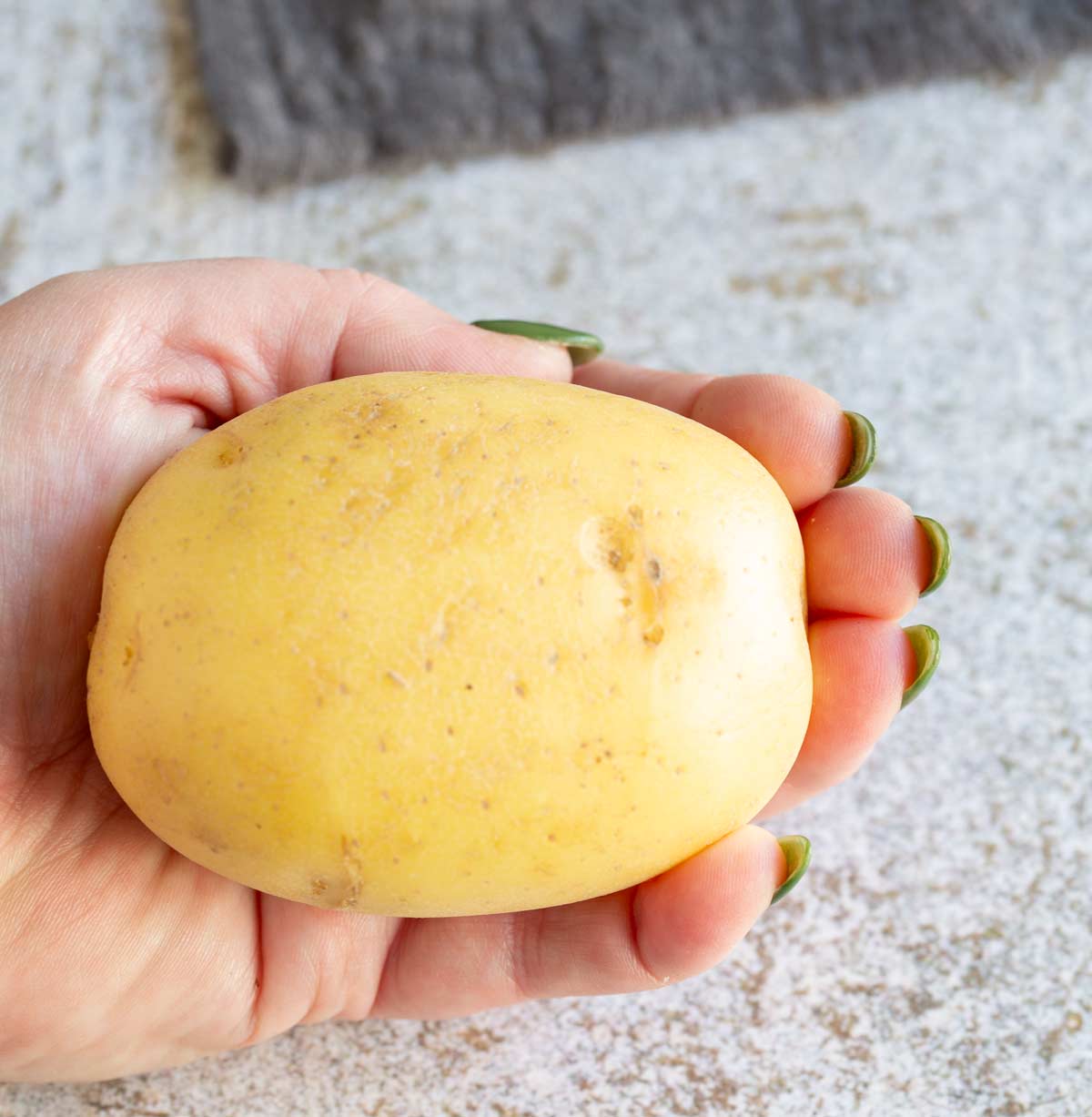 a hand holding a medium sized potato for size comparison