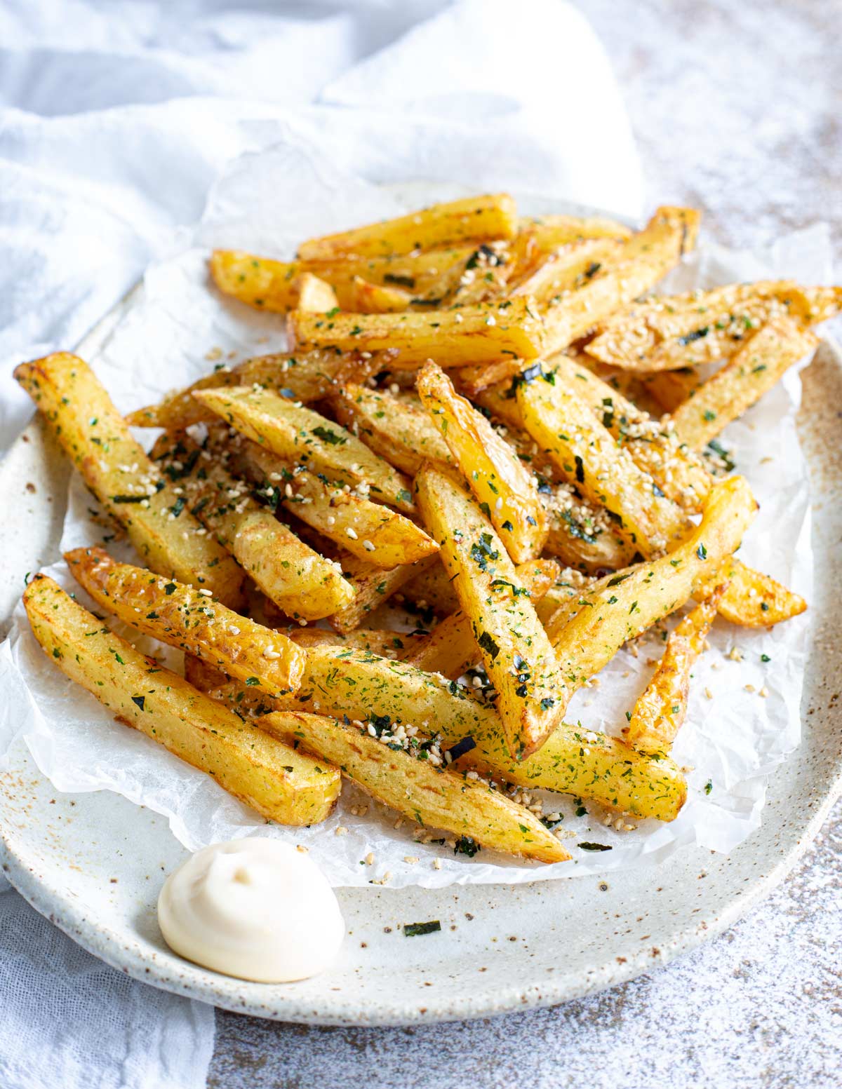 a rustic plate piled with furikake fries with a dollop of mayo