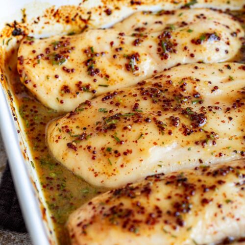 close up on a chicken breasts with mustard seeds on top