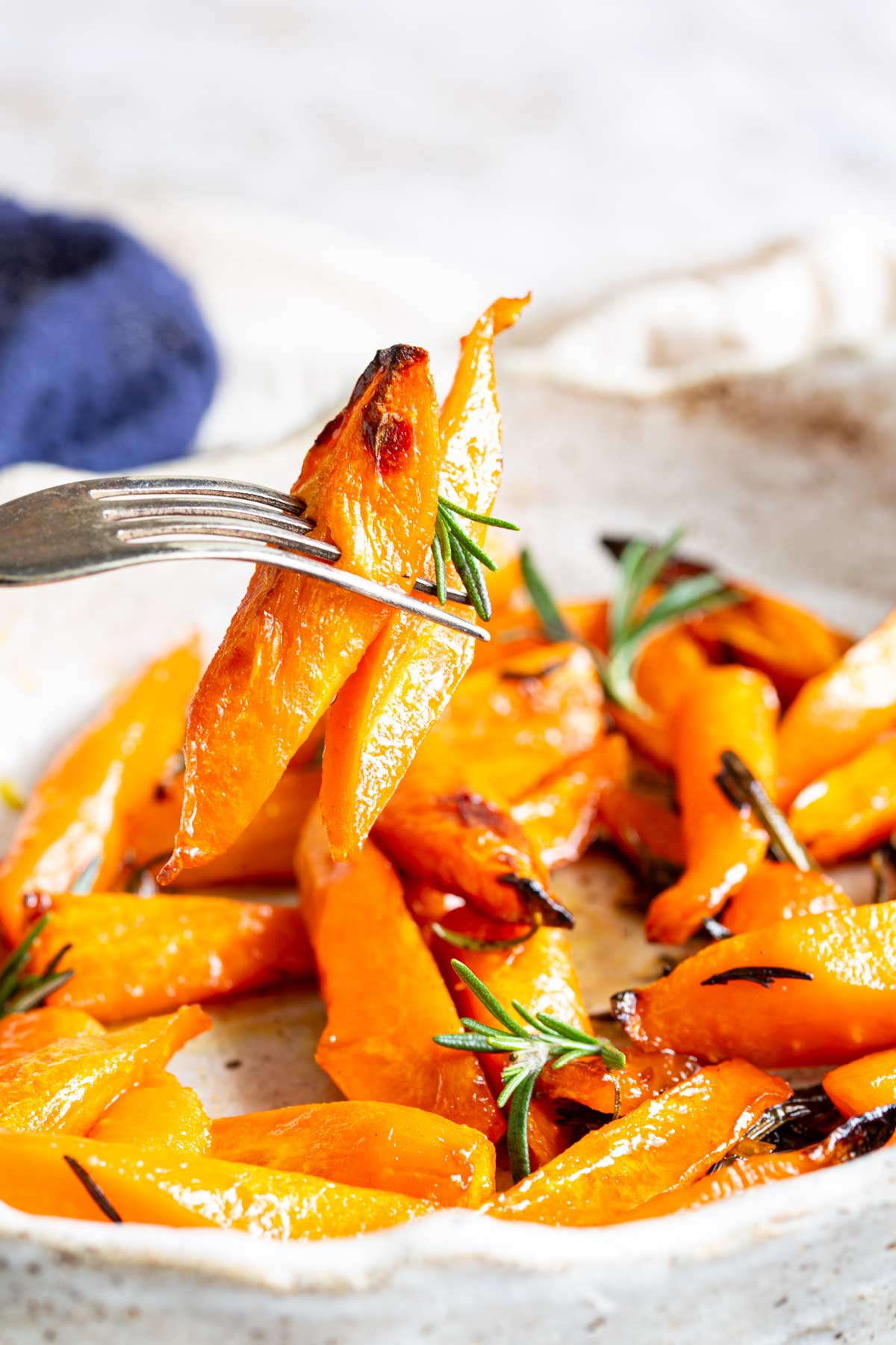 a fork picking up carrots from a roasting dish