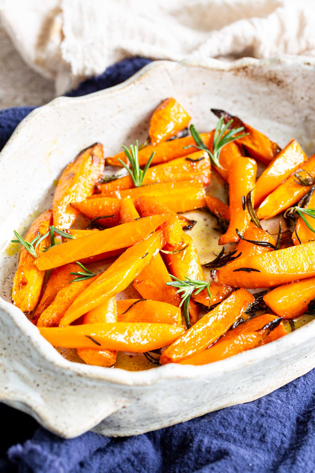 a rustic dish of roasted carrots with spring of rosemary as garnish