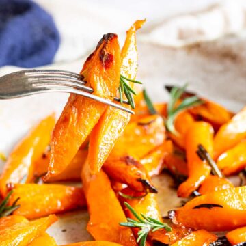 a fork with two chunks of carrot on it and a little rosemary sprig