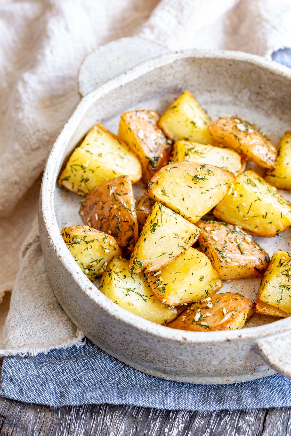 potatoes in a round stone dish with handles on a blue napkin