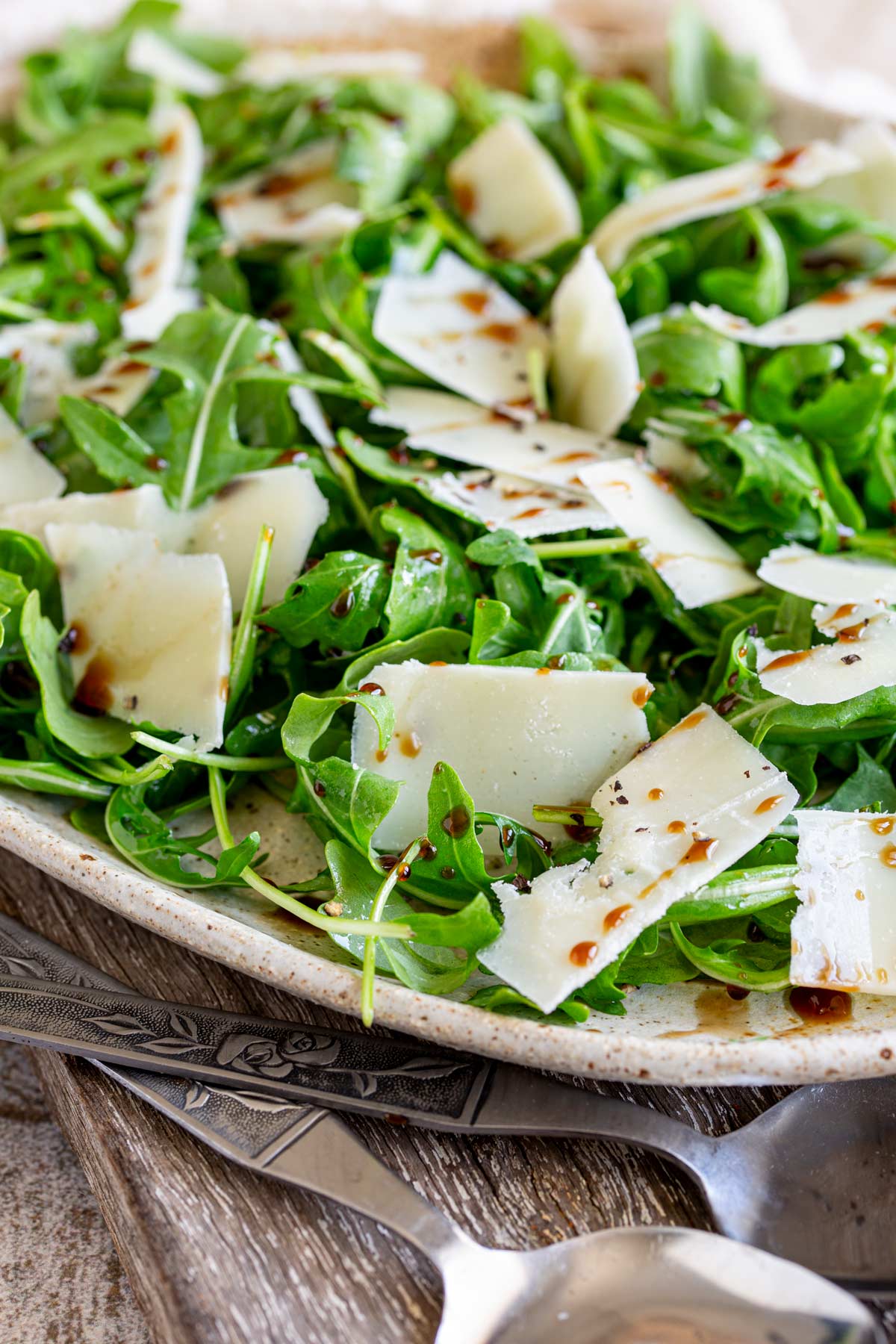 rocket and parmesan salad on a rustic table with serving utensils