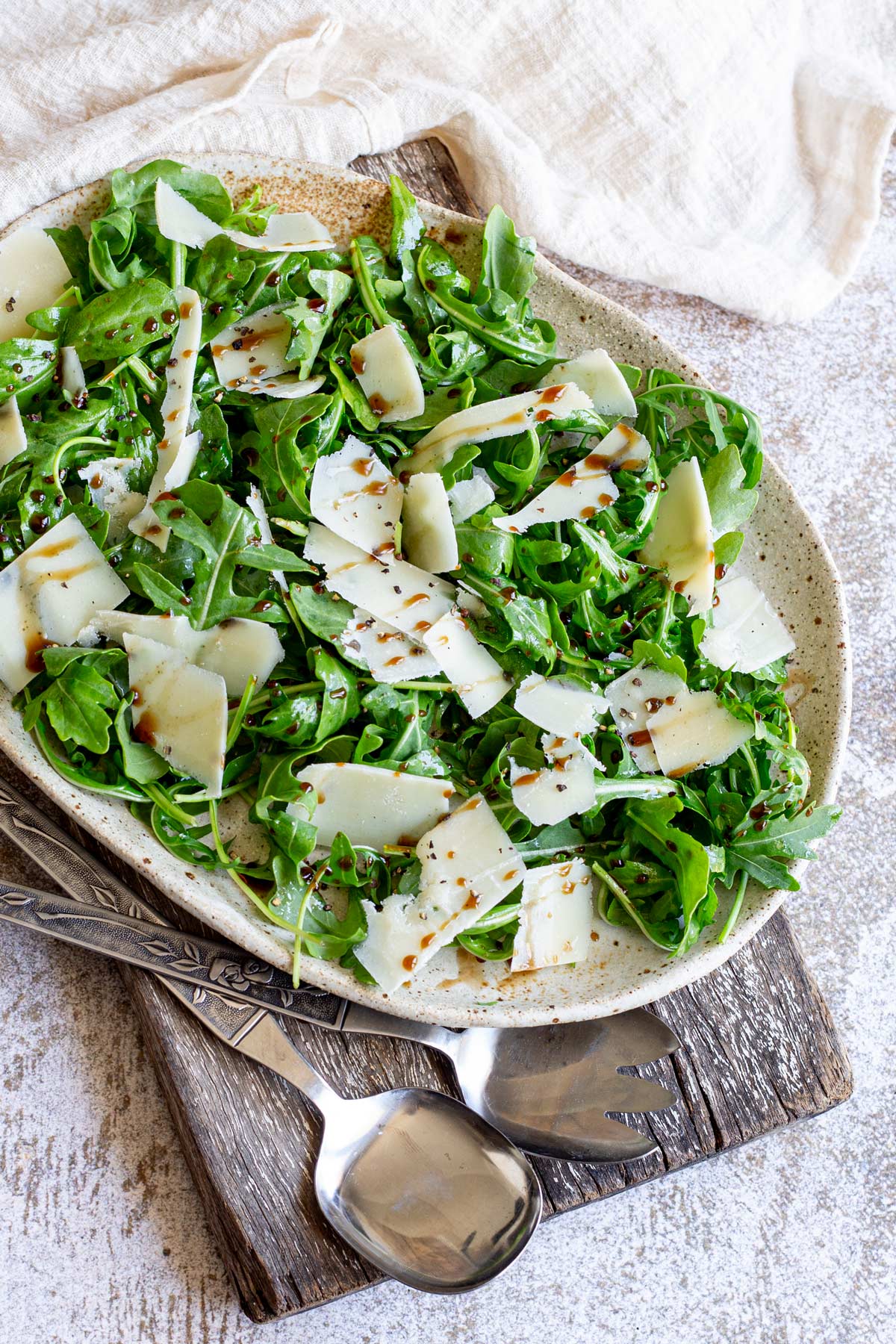 a stone table with a wooden board and rustic plate of salad