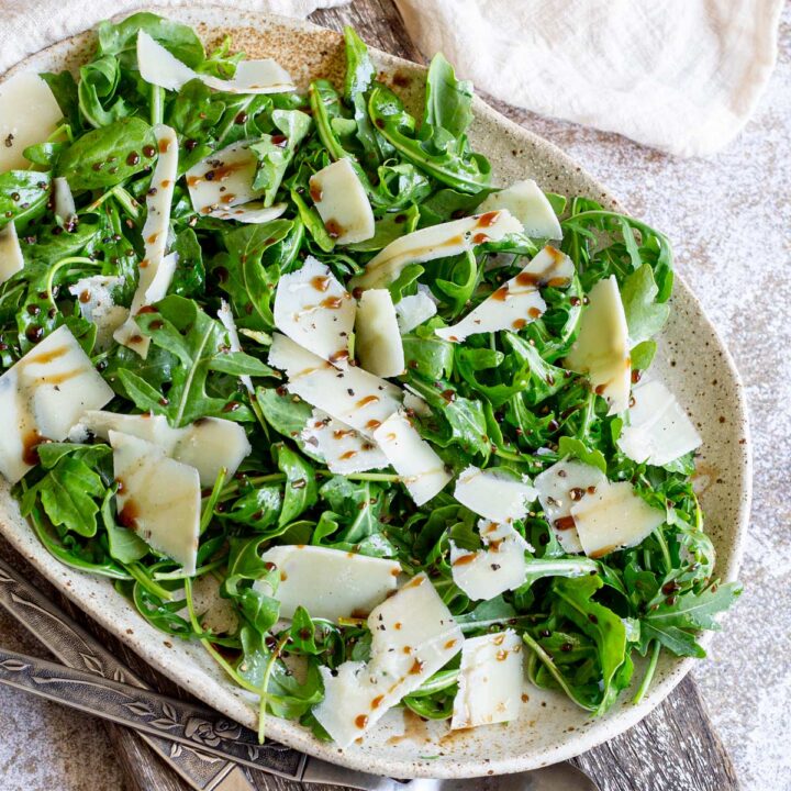 overhead shot of a greet salad with parmesan on a rustic oval plate