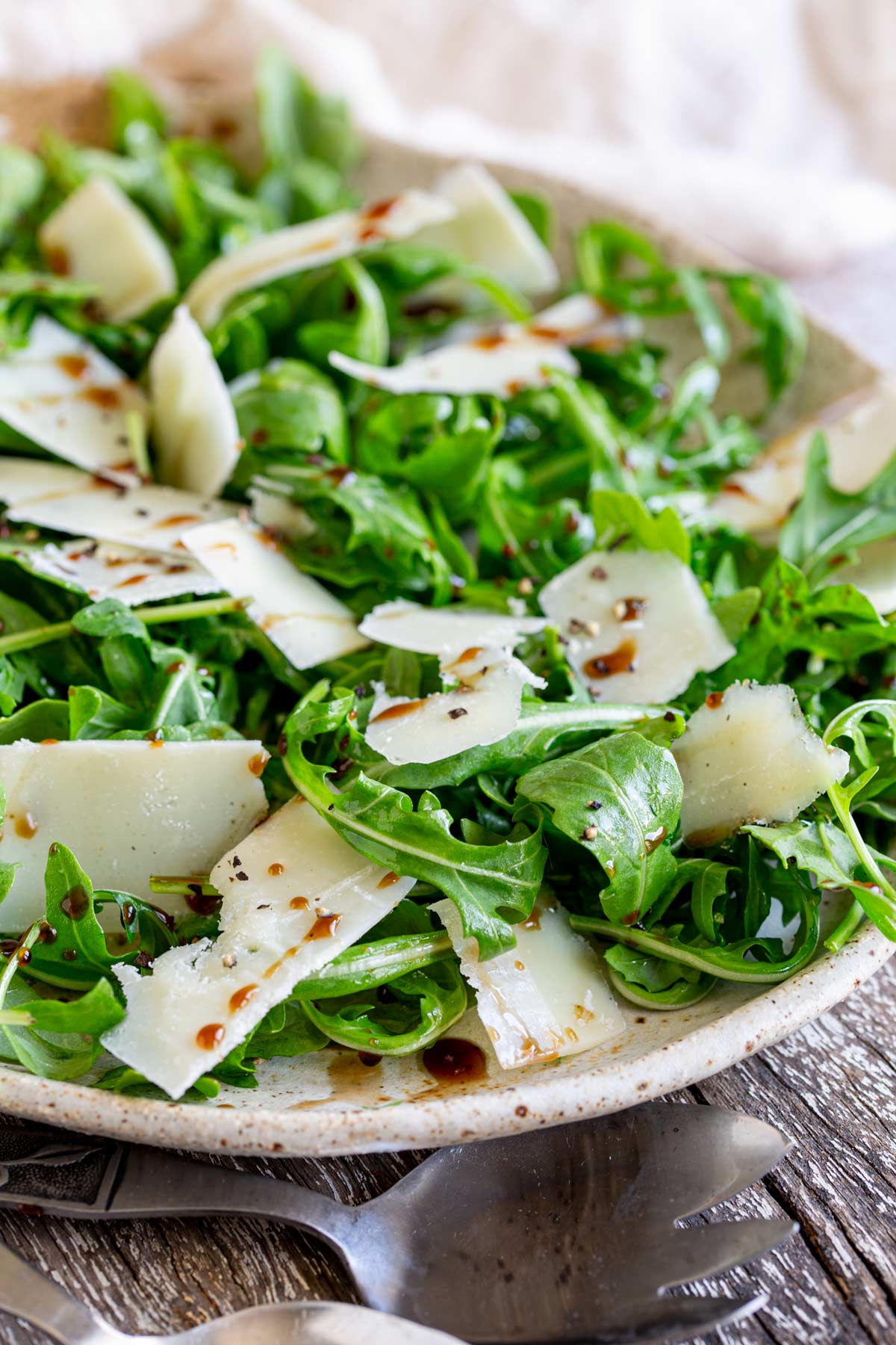 rocket leaves with balsamic glaze on them on a large serving plate