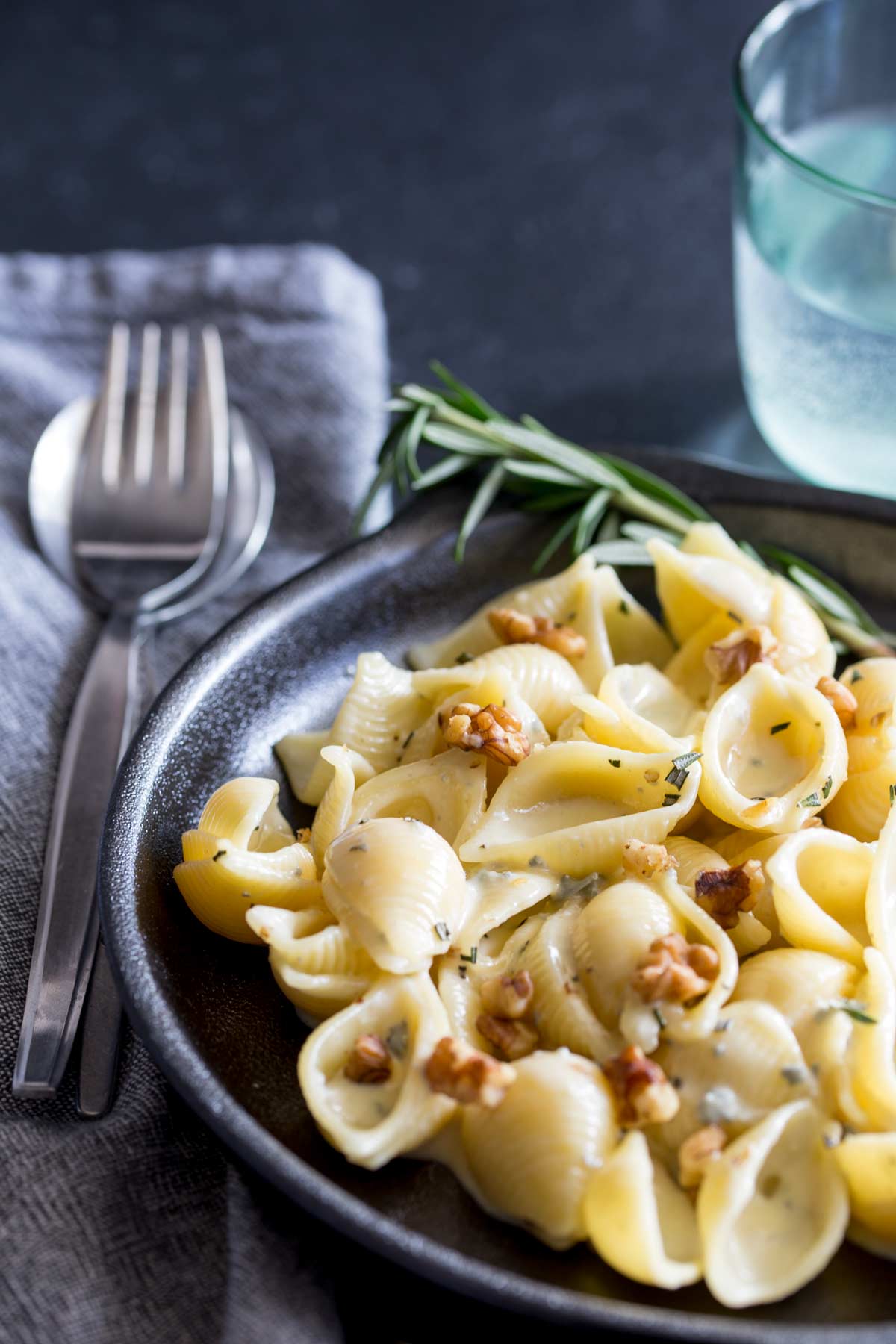 close up of the black plate of creamy pasta, with toasted walnuts and fresh rosemary