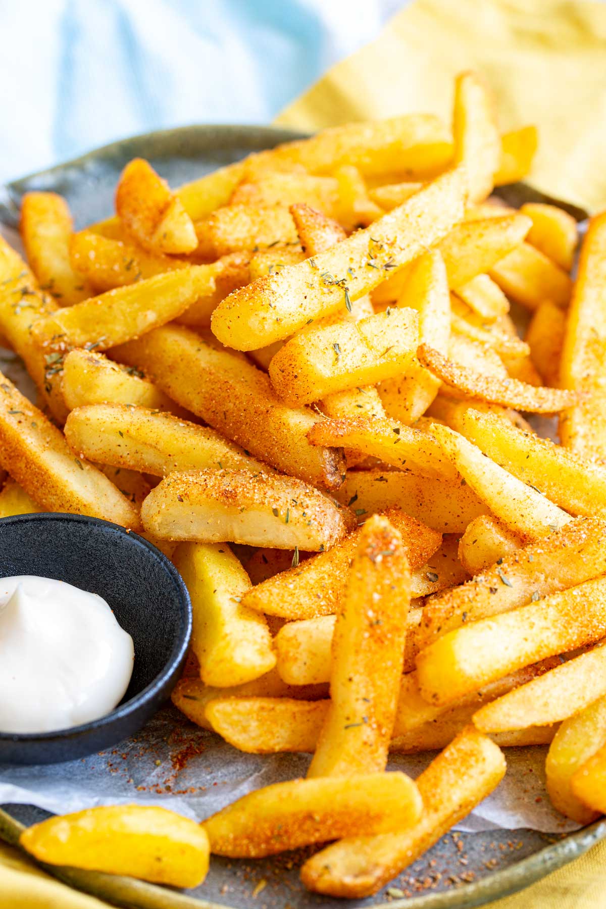 seasoned fries on a lined plate with a pot of mayo