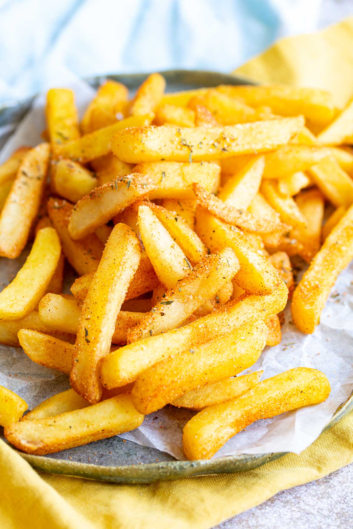 a rustic blue plate with parchment paper on it and a pile of fries