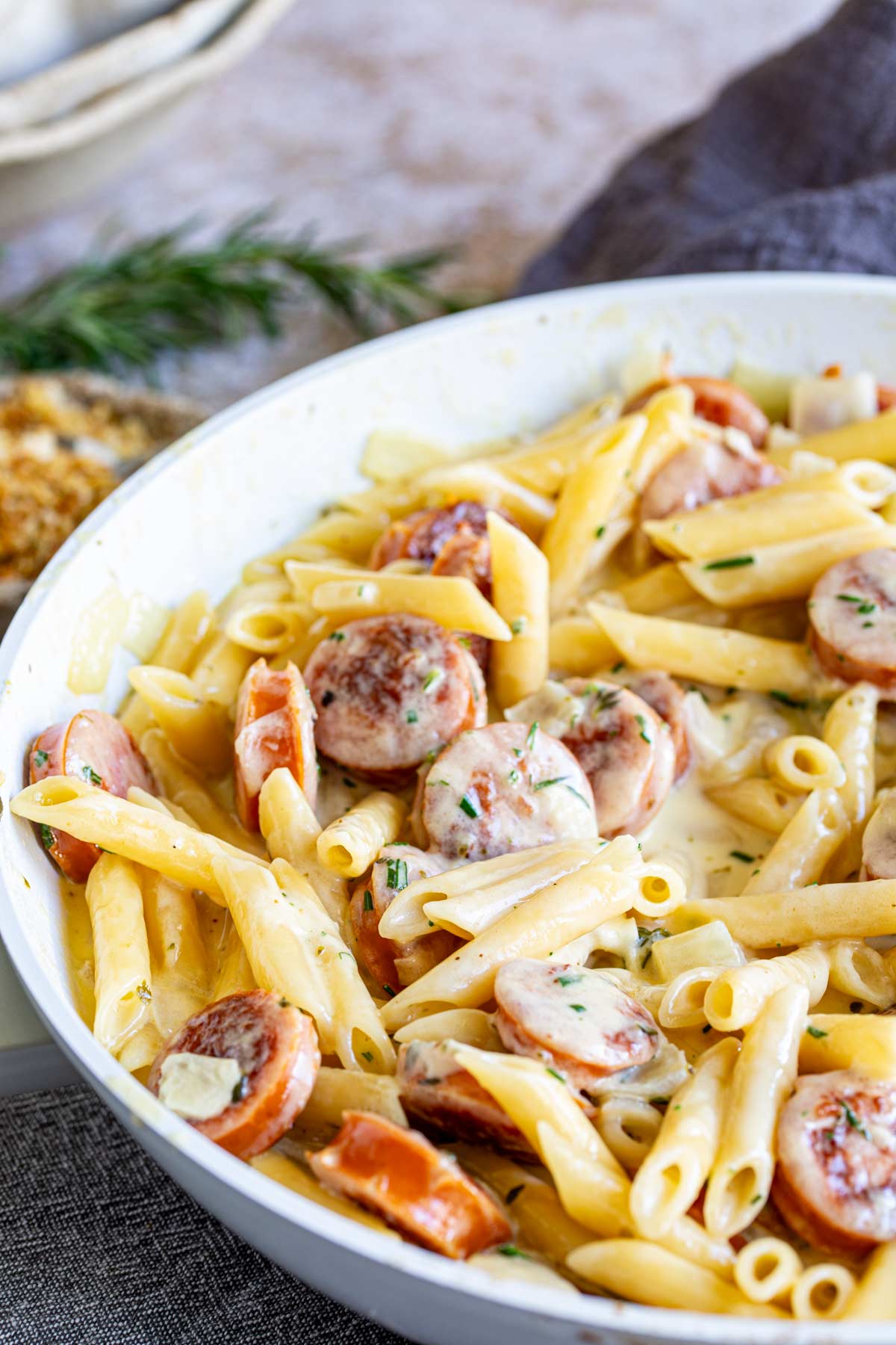 creamy cheesy sausage pasta in a large white skillet