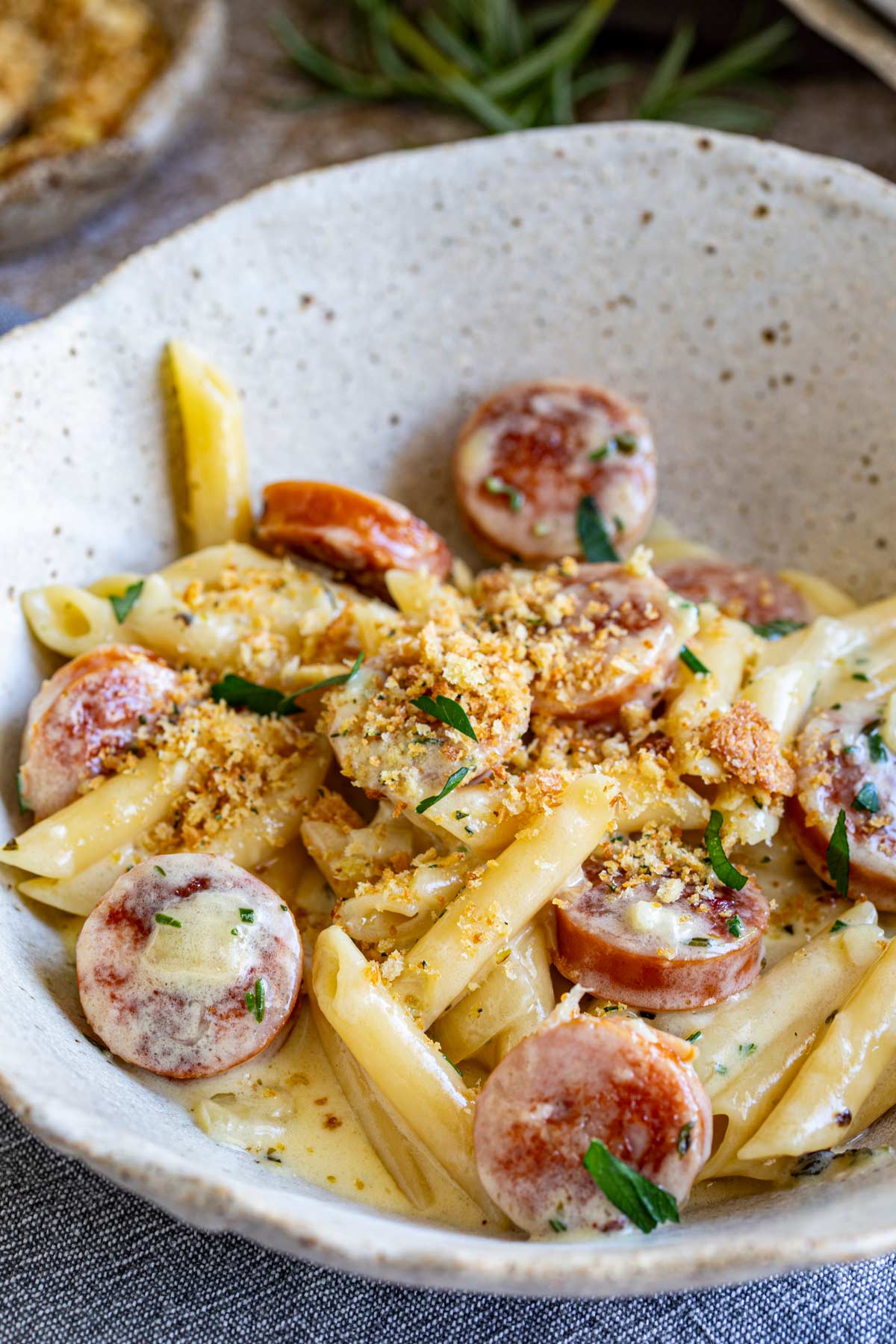 a rustic bowl filled with cheesy sausage pasta topped with crispy breadcrumbs