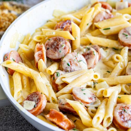 close up on the kielbasa in a cheese sauce in a pan with pasta