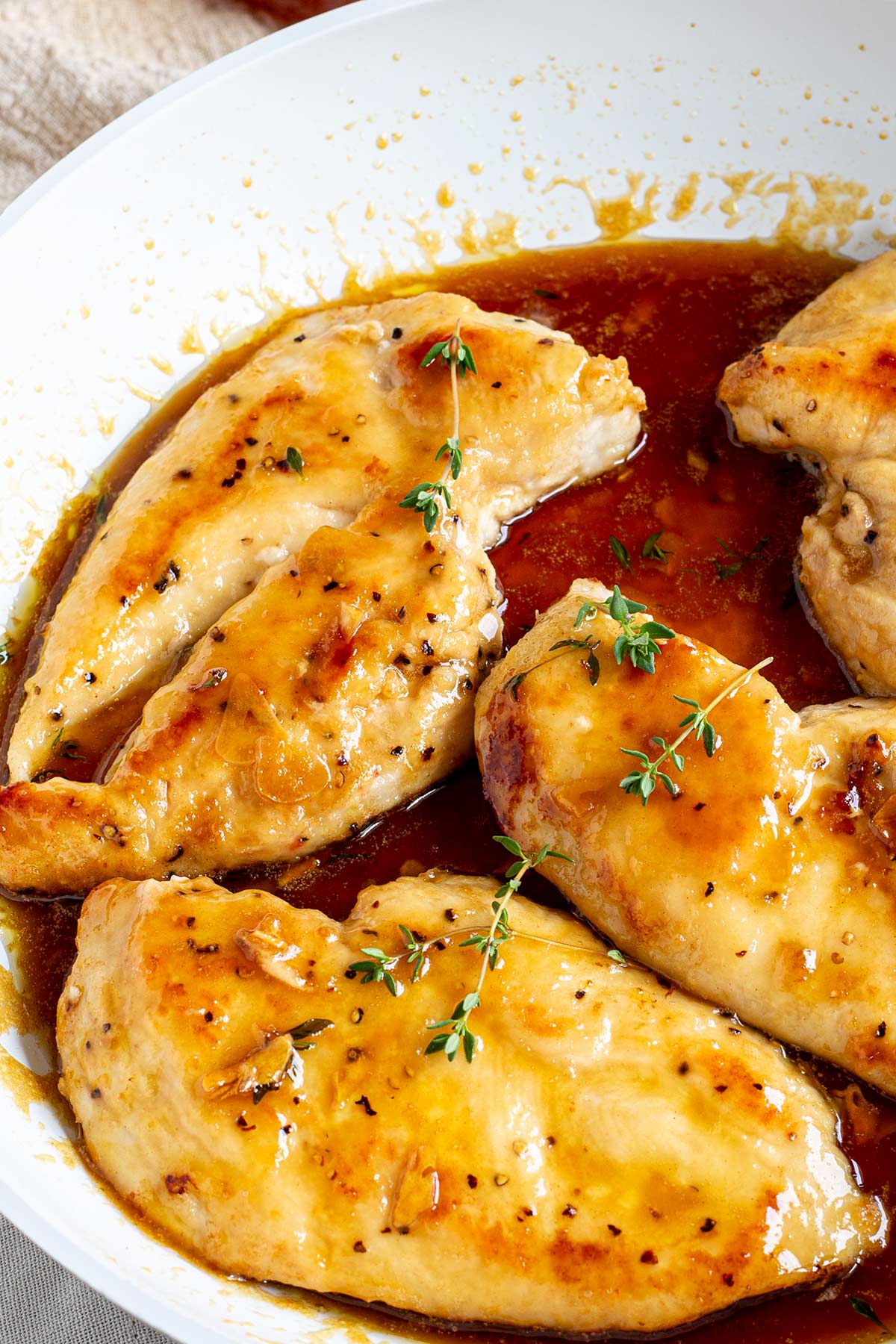 overhead of chicken breasts in a skillet garnished with a sprig of thyme