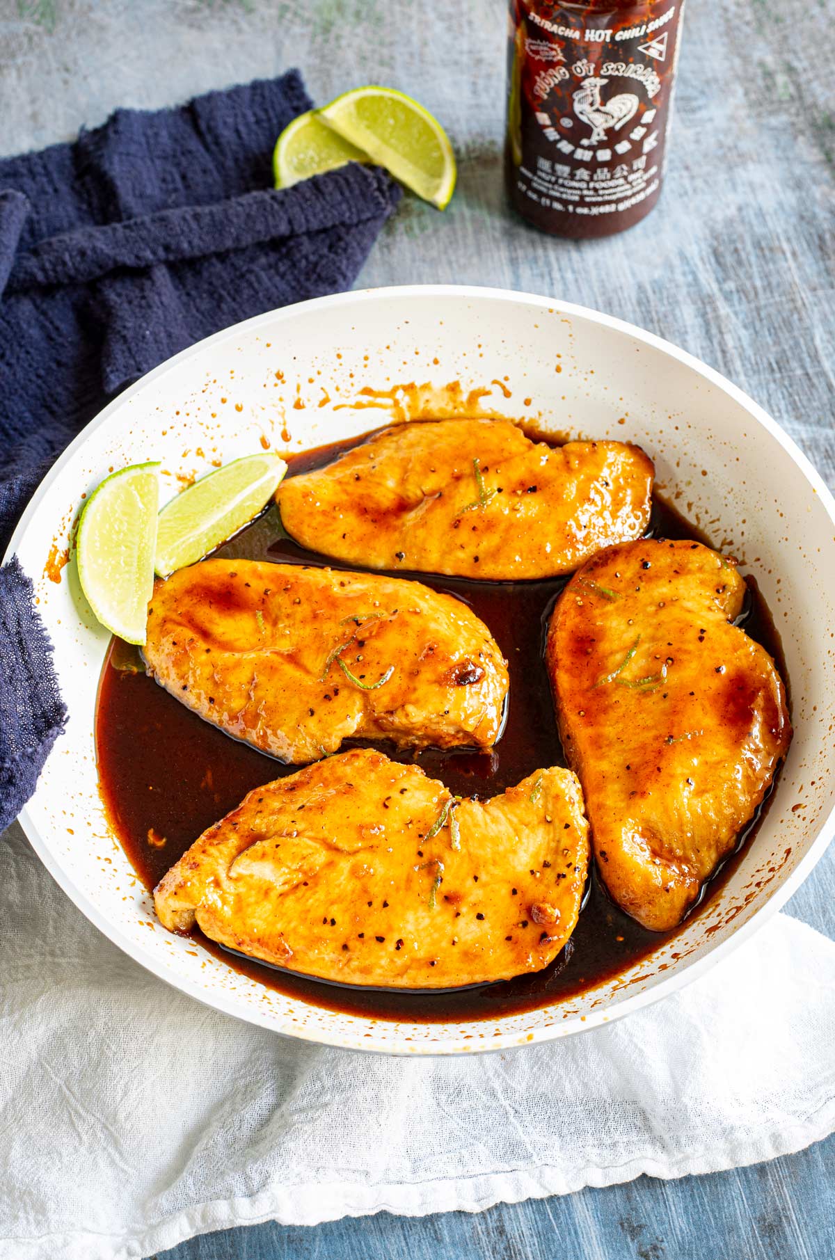 overhead of a skillet with 4 chicken breasts in a honey sriracha sauce