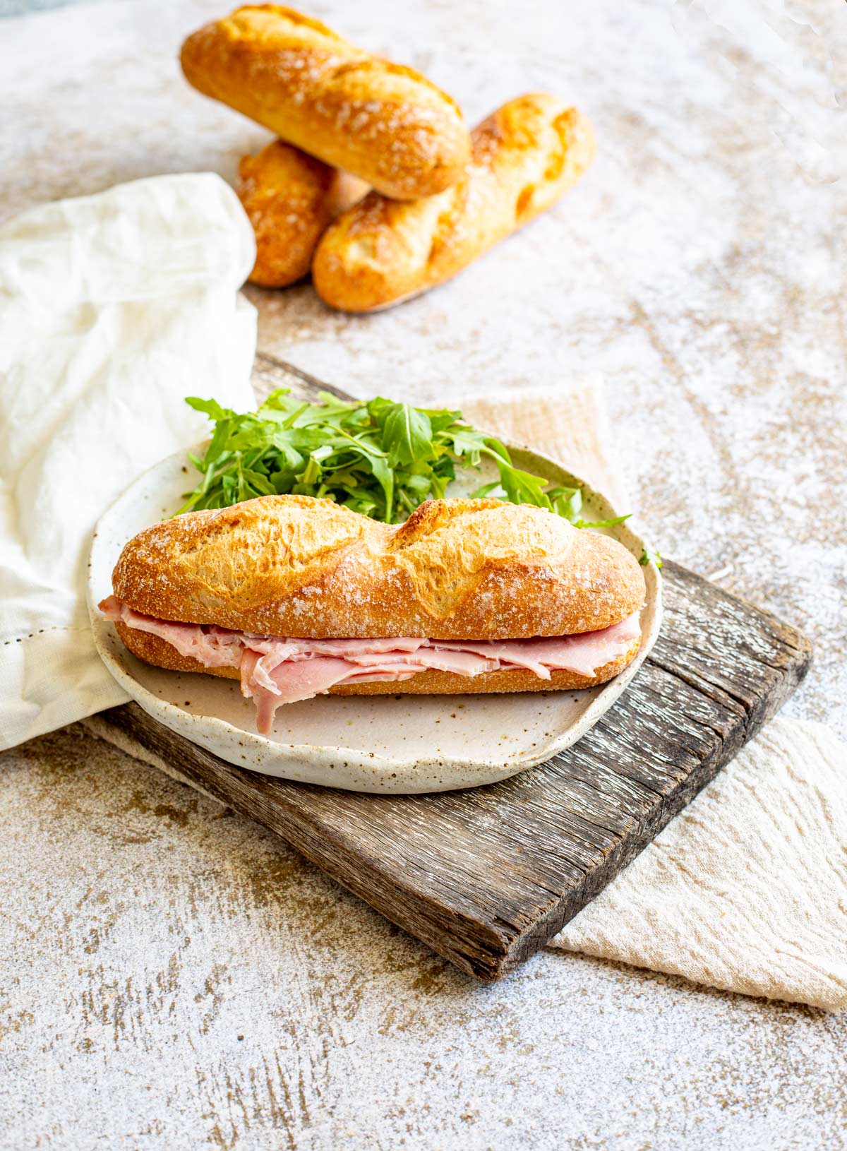 a baguette sandwich on a plate on a wooden board on a rustic table