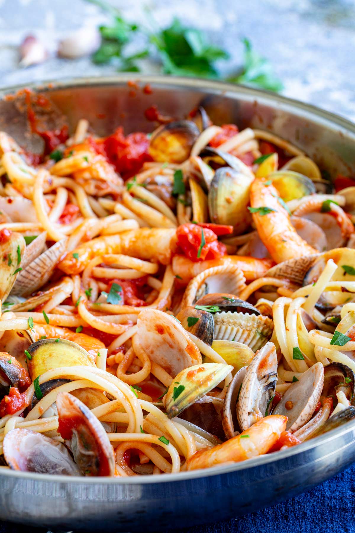 clams in their shell stirred through a pan of linguine