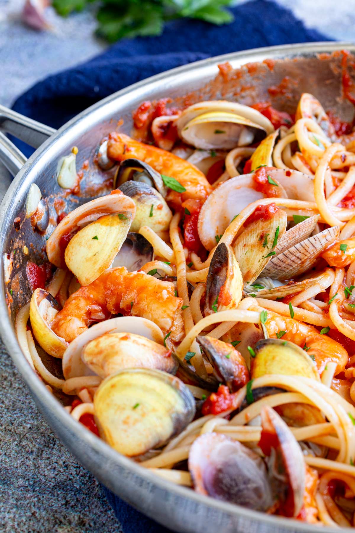 shrimp and clams in their shells in a pan with tomato pasta