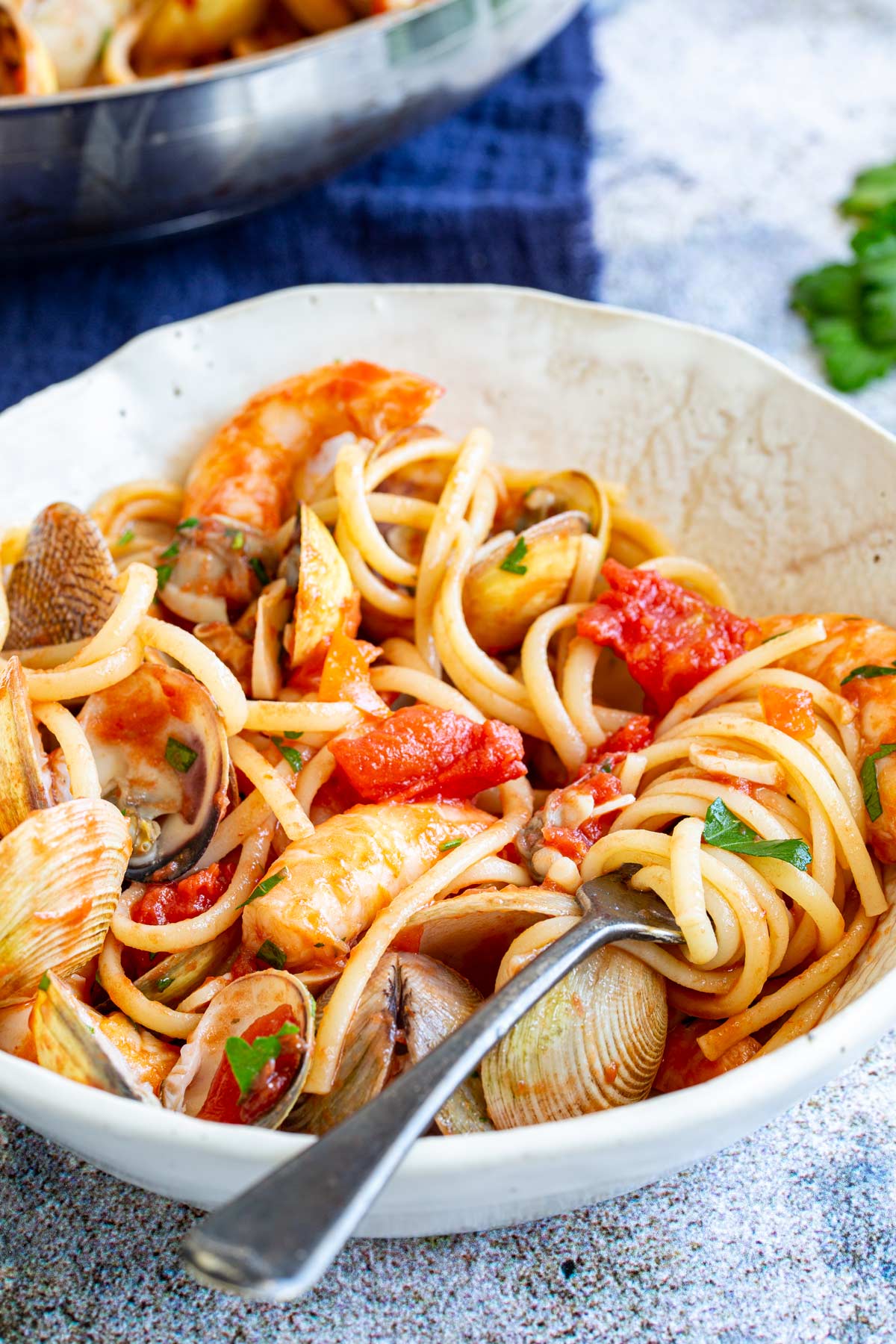 a fork in a bowl of linguine with tomato shrimp and clam sauce