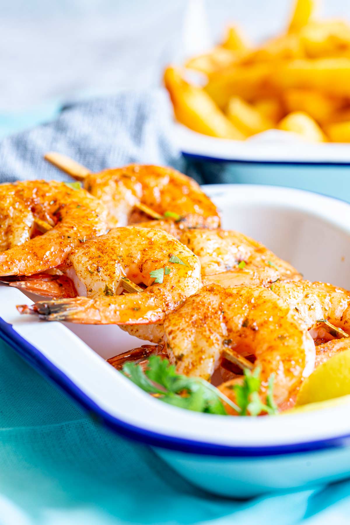 a dish of shrimp skewers and a dish of fries on a table