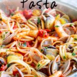pin image: shrimp and clam pasta in a pan with text overlaid