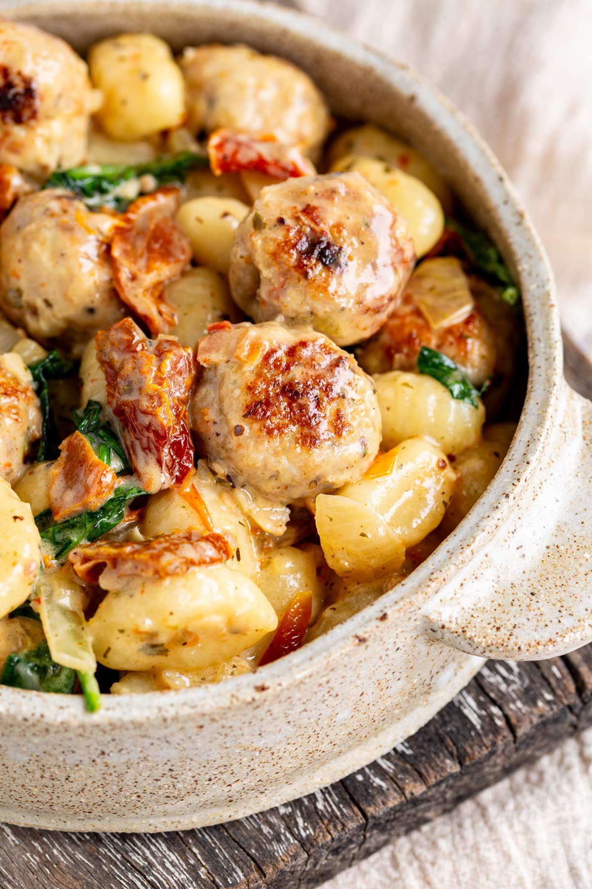 close up on a bowl of chicken meatballs and gnocchi in a creamy sauce