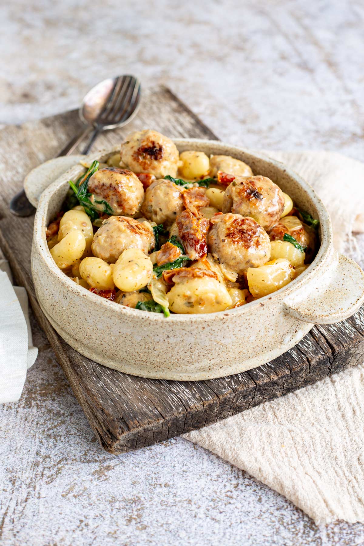rustic dish with meatballs and gnocchi on a wooden board with a linen napkin