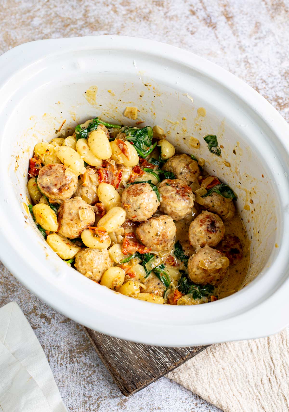 a slow cooker filled with gnocchi and meatballs in a creamy sauce