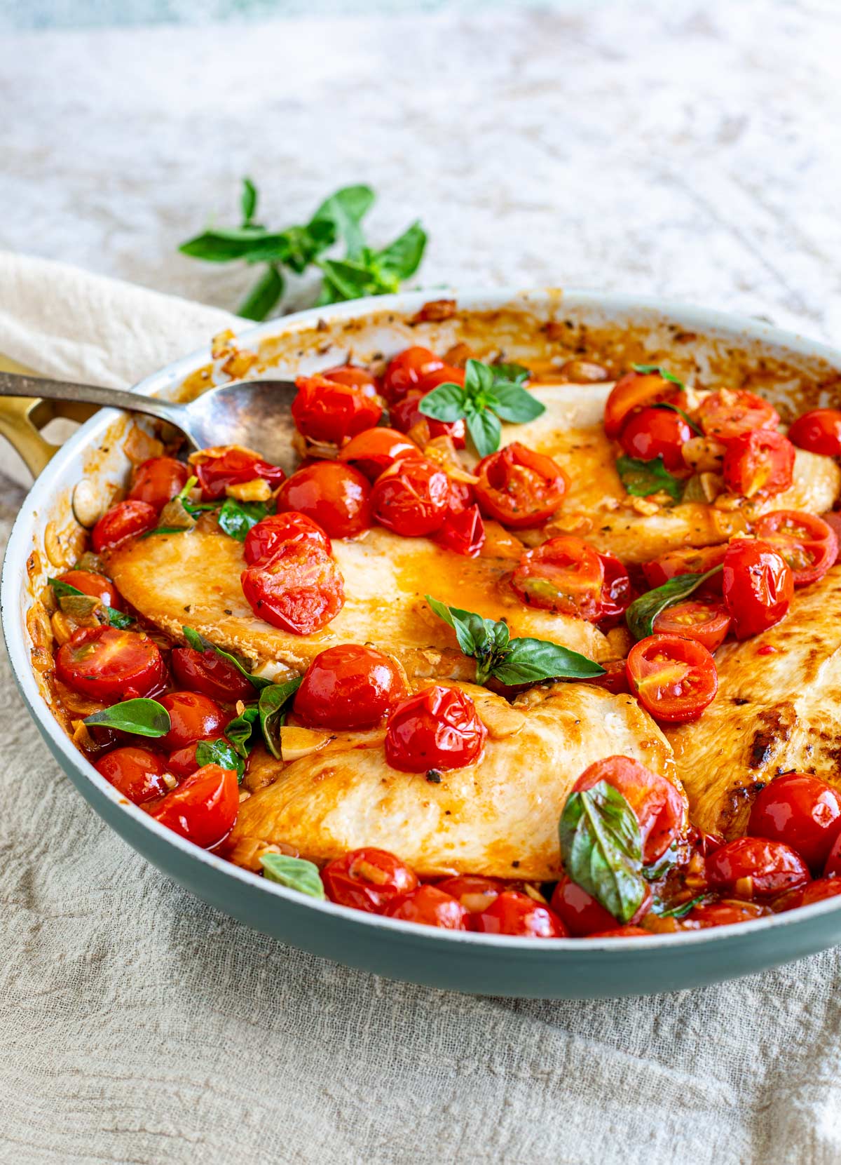 a skillet filled with chicken in a. tomato sauce on a rustic table