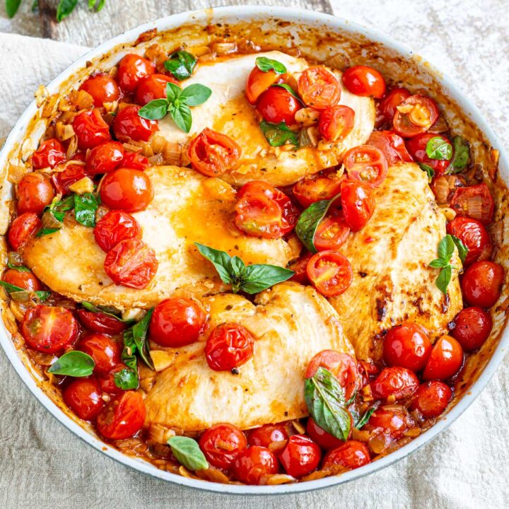 overhead shot of a skillet with 4 cooked chicken breasts in a cherry tomato sauce
