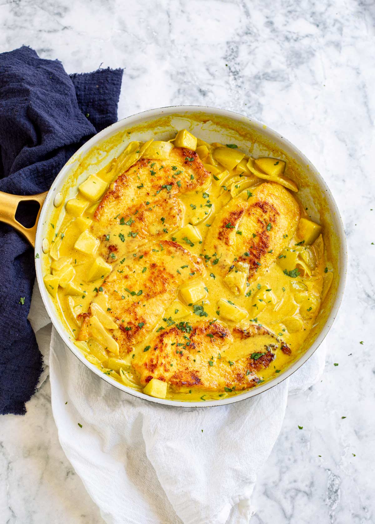 overhead view of a skillet of chicken breasts in a curry sauce