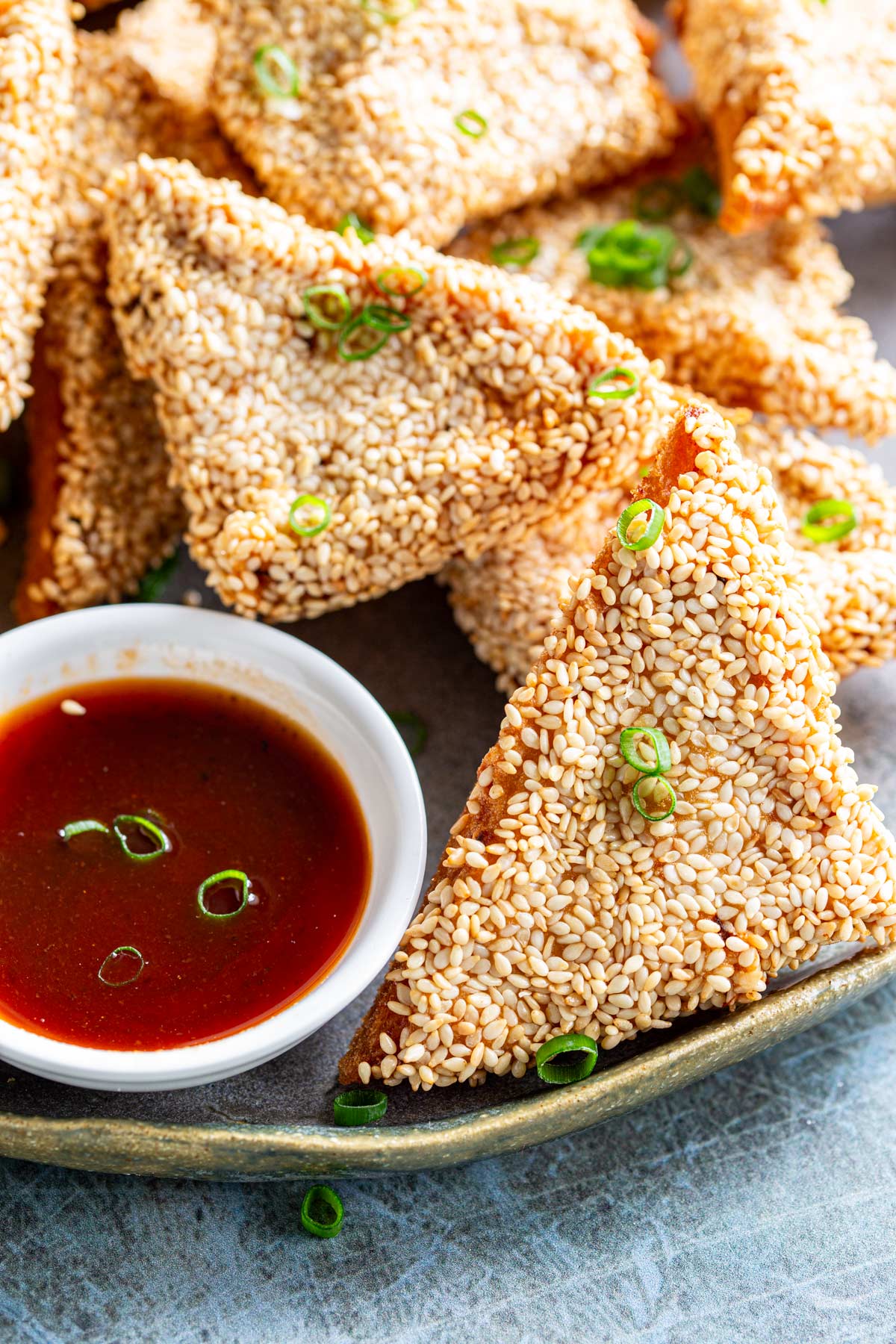 close up on a sesame seed coated fried triangle of chicken toast