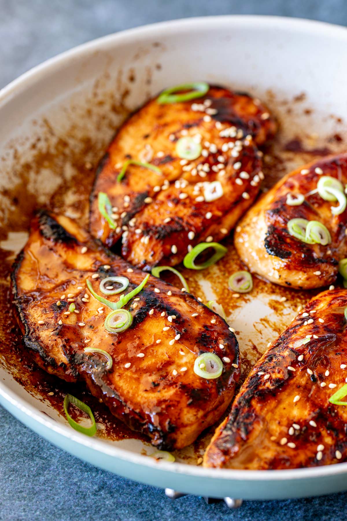 Honey miso chicken fillets in a skillet, garnished with green onions.