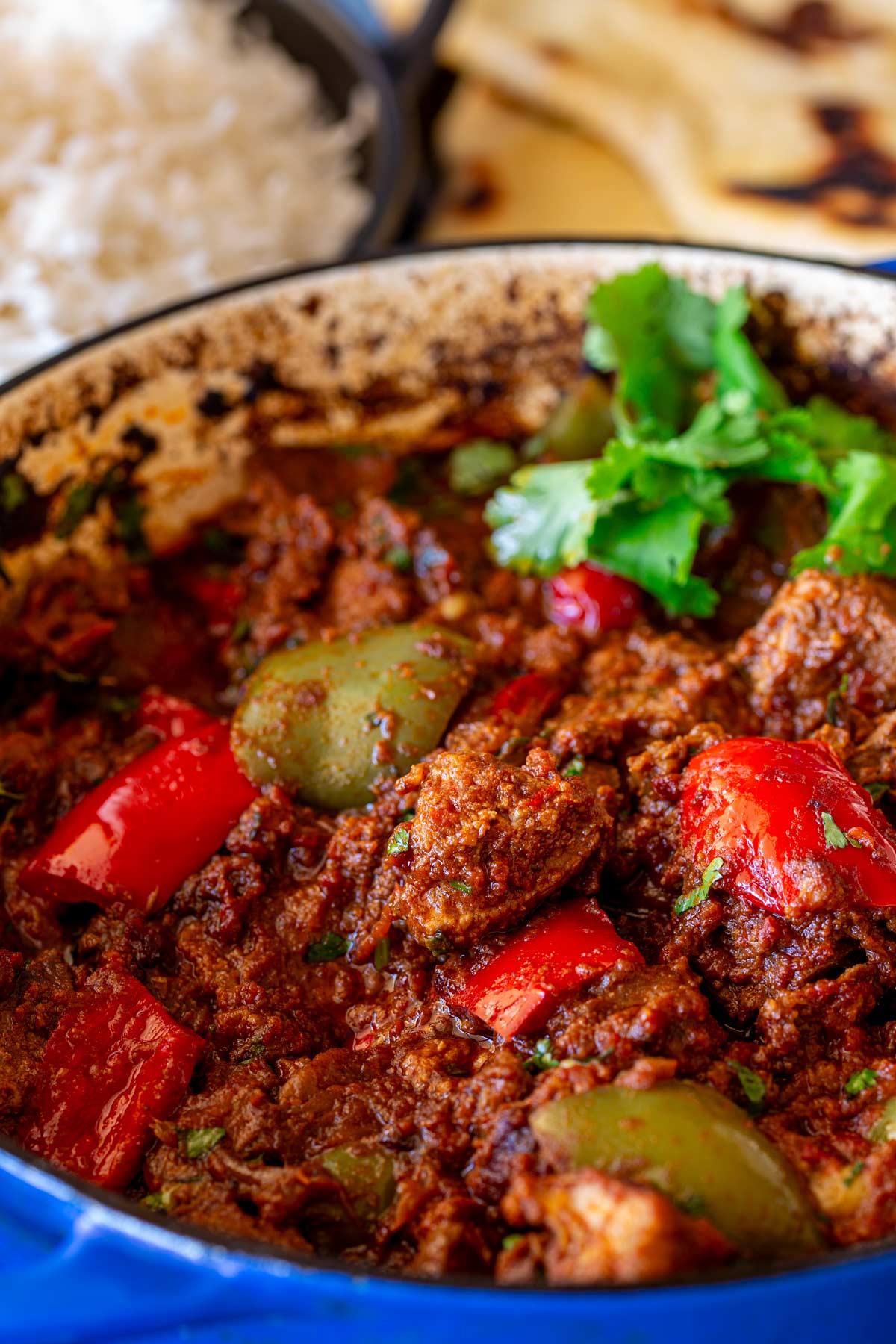 Close-up of a rich, spiced pork curry with chunks of pork and bell peppers, garnished with cilantro