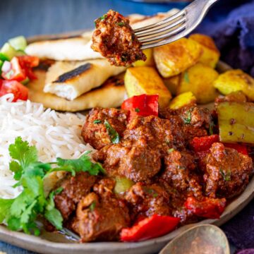 close up on a fork holding a piece of pork curry