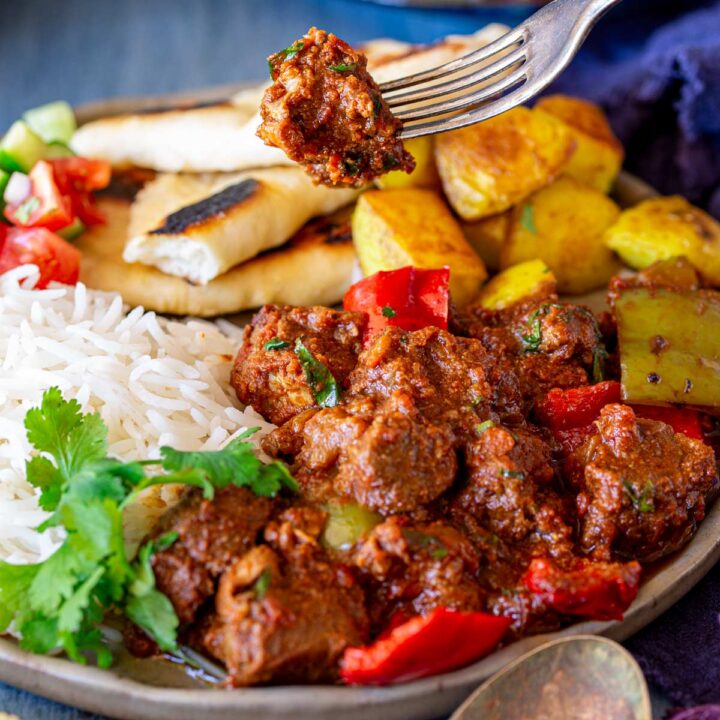 close up on a fork holding a piece of pork curry