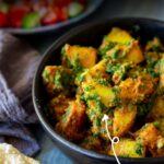 pin image: Saag aloo in a black bowl with text overlaid