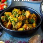 pin image: Saag aloo in a black bowl with text overlaid