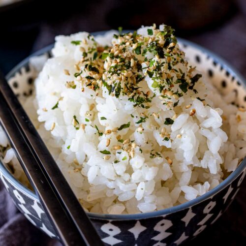 extreme close up of a small bowl of sticky rice sprinkled with furikake.